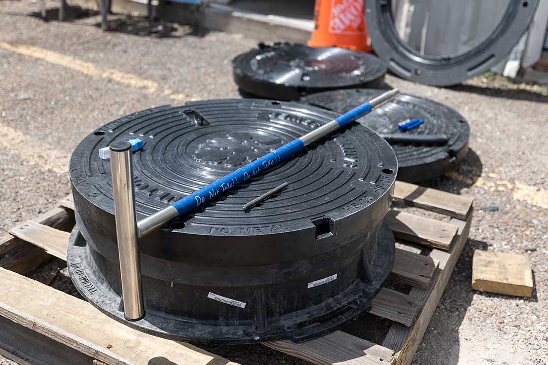 Un objeto redondo negro, probablemente una tapa de registro, colocado sobre un palé, que muestra opciones para seleccionar la tapa adecuada.